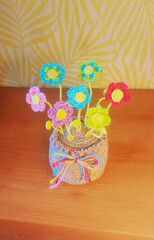 A crochet basket made from colorful jute with flowers