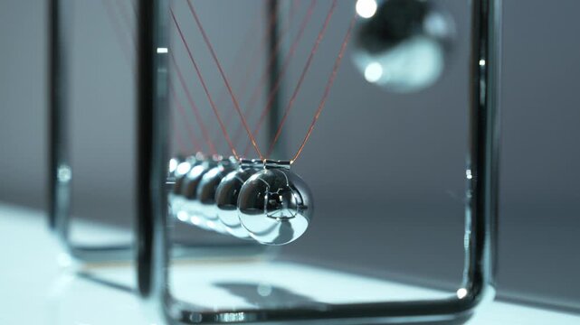 Newton's Cradle Pendulum with Red Laser Light Trails Demonstrating Physics Motion and Energy Transfer