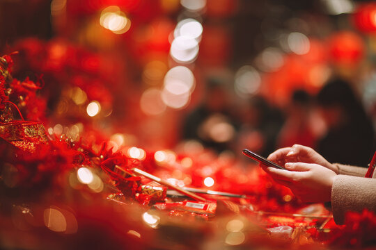 Mobile payment during cny celebration with festive red decoration and blurred background creating joyful atmosphere for digital transaction in traditional setting