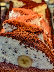 Banana Cream Cake Roll with Chocolate Sponge Layers and Whipped Cream Filling Sliced Display. Sweets Food Background 