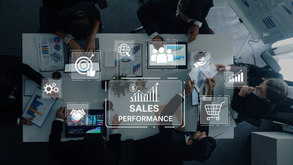 Aerial view of a business team collaborating on sales performance analysis with digital devices showcasing graphs, data, and strategic insights in a modern office environment. Trope