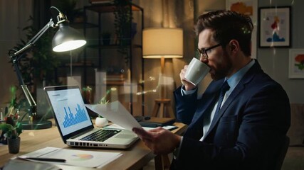 Caucasian middle-aged businessman stock market analyst working in front of computer screen analyzing trading data late at night, staring at a monitor with stock indexes and economic charts - Powered by Adobe