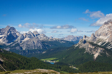 Panoramic view from Tre Cime di Lavaredo towards Lake Misurina with Sorapiss mountain at left and Monte Cristallo right; Dolomite peaks above forest in a beautiful landscape against blue sky