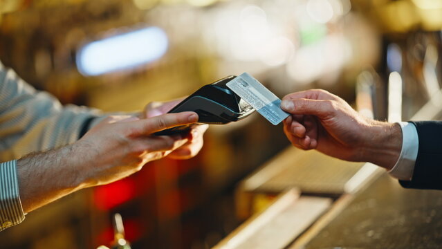 Unknown man paying bill with credit card in evening restaurant counter closeup
