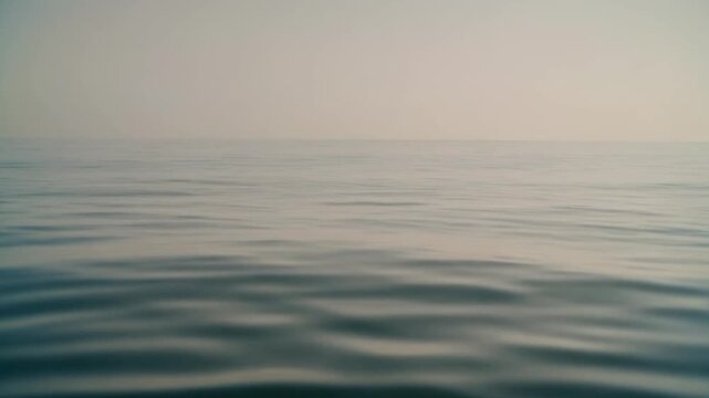 Serene waters merge seamlessly with a soft, hazy sky, creating an atmospheric and peaceful horizon that stretches into the infinite, conveying a deep sense of calm and boundless tranquility