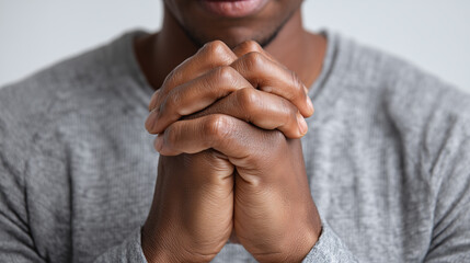 Close up of hands pressed together tightly in gesture of hope and contemplation, person wearing gray sweater, emotional and thoughtful mood