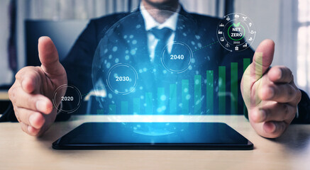 A businessman presents a futuristic digital interface showcasing sustainability projections and...