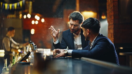 Bar clients getting drunk sitting lounge smoking cigarettes together closeup