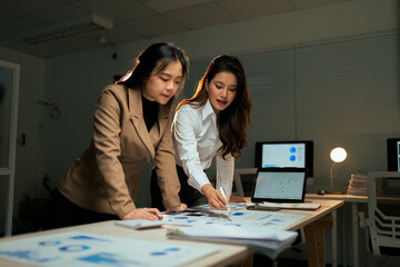 Businesswomen working overtime analyzing data in office