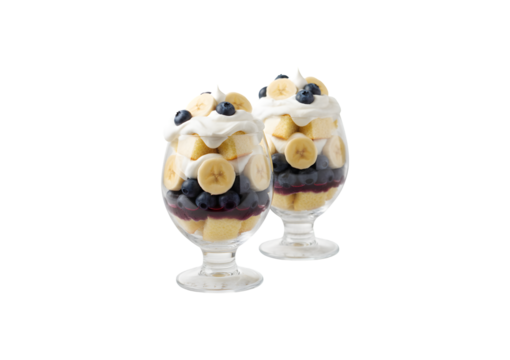 Yummy trifle dessert. Featuring banana, blueberries, sponge cake, and whipped cream in glasses on a white wooden table, leaving room for text. Perfect for any occasion!