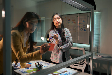 Asian business women brainstorming late night in office