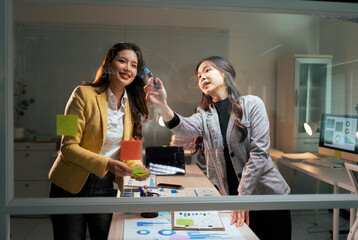 Businesswomen collaborating on glass board brainstorming new ideas