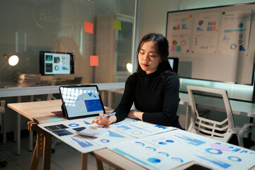 Professional woman analyzing financial data and business reports late night