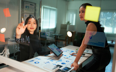 Young Asian businesswomen planning strategy using glass board