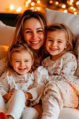 Mother playing with two daughters, sitting on a sofa covered with a blanket
