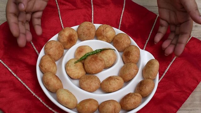 serving indian snack kachodi in a ceramic palatter. hand putting the plate.