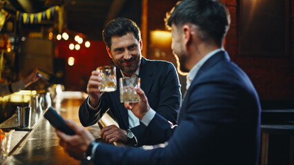 Happy colleagues toasting cocktails relaxing together after work evening closeup