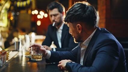 Tipsy friends holding bourbon glasses enjoying warm glowing ambiance closeup