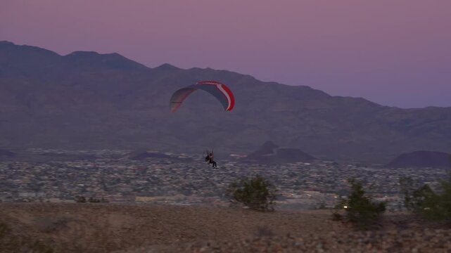 A man flying a para-plane at low level in the desert