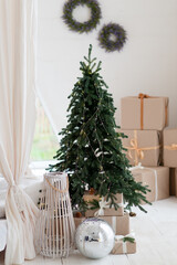 Decorated Christmas tree and gift boxes over white wall and window, room interior