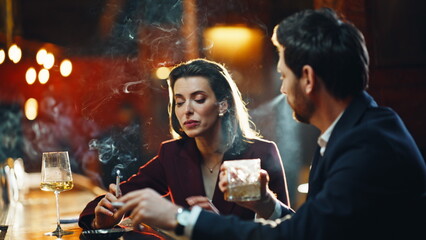 Partying couple sitting together enjoying tobacco sticks in soft lights closeup