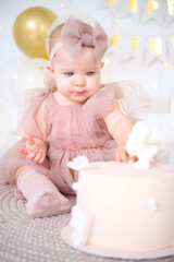 little beautiful blue-eyed girl celebrates her first birthday and tastes her first birthday cake