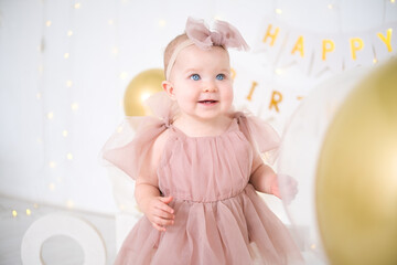 little blue-eyed girl in pink dress celebrates her first birthday 