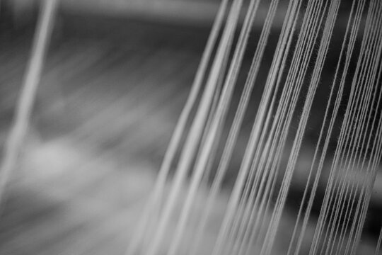 A close-up view of weaving threads pulled tightly across a loom during fabric production.