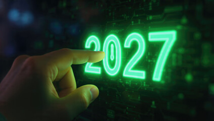 A hand interacts with a glowing green digital display showing "2027" on a futuristic circuit board background, symbolizing future technology and planning.
