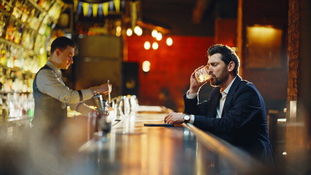 Drunk man sipping alcohol sitting bar counter closeup. Relaxed guy paying waiter