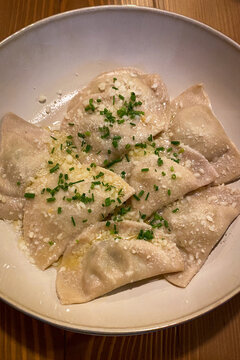Traditional Tyrolean Schlutzkrapfen &mdash; spinach-ricotta filled pasta with brown butter, chive and grated cheese &mdash; served in South Tyrol, Italy