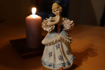 Zur Adventszeit steht eine Porzellanfigur vor einer brennenden Kerze