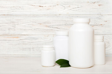 supplement pills with medicine bottle health care and medical top view. Vitamin tablets. Top view mockup bottle for pills and vitamins with green leaves, natural organic bio supplement, copy space