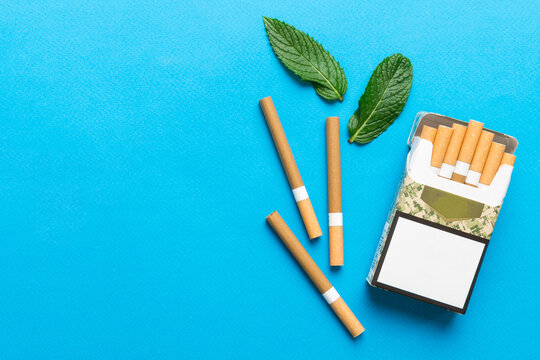 Pack of menthol cigarettes and fresh mint on colored table, Menthol cigarettes top view flat lay