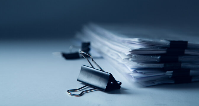 Stack of business papers with binder clips on gray background. Selective focus.