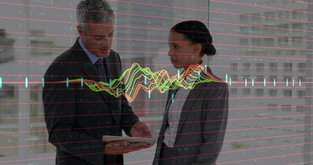 Pointing man in suit holding tablet, woman in blazer observing financial chart overlay in office