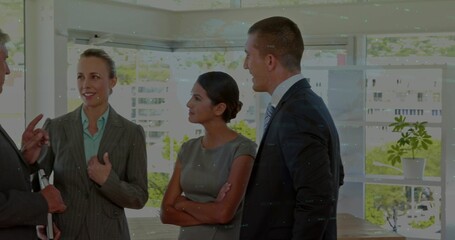Discussing, four colleagues in business attire meeting near windows holding documents, plant behind