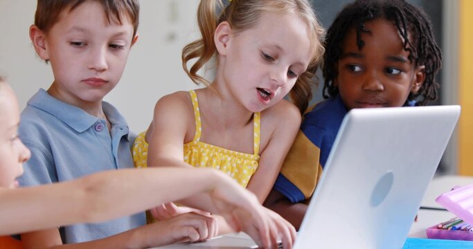 Pointing blonde girl in yellow dress reading at school table, with silver laptop, pink pencil case - Powered by Adobe