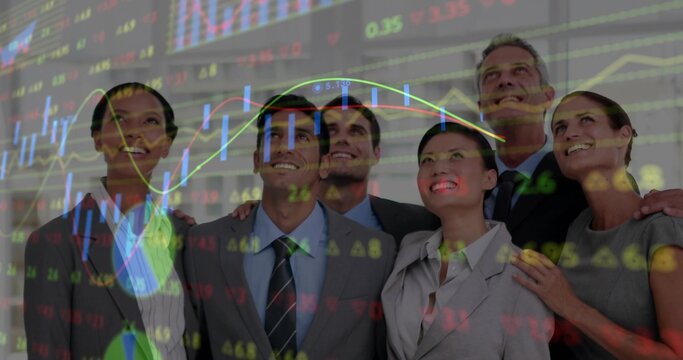 Smiling corporate team in suits looking upward in office, showing projected charts and tickers