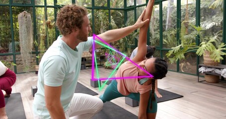 Guiding man kneeling by woman aligning on mat in greenhouse, teal leggings magenta-green triangles