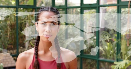 Standing Pacific Islander woman in red tank top with braids in greenhouse, map overlay and bricks