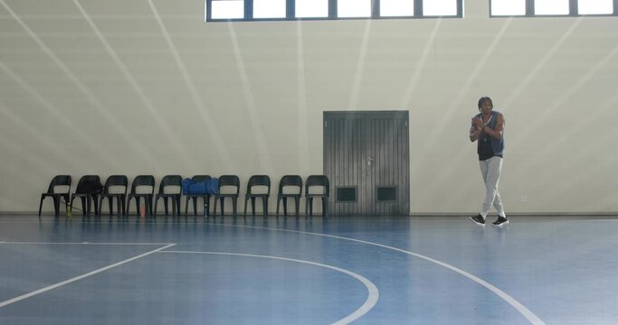 Standing man wearing vest and pants near wall in gym, with chairs, blue jacket, copy space