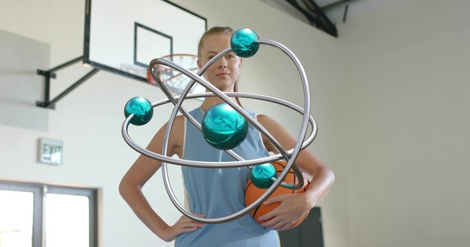 Holding orange basketball at hip, player in blue jersey standing in gym, orbital sculpture floating