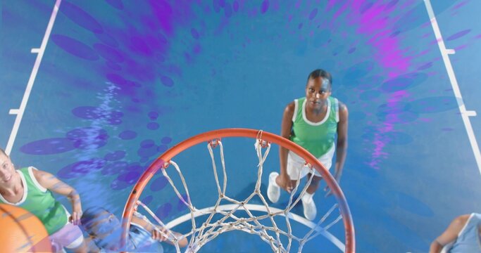 Jumping green sleeveless jersey player in shorts reaching rim at gym with hoop and net, basketball
