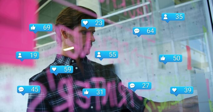 Pointing man in plaid shirt annotating glass board at office, pink marker notes and social bubbles