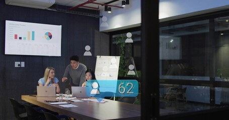 Pointing man wearing dark sweater, team using laptops at meeting table, showing charts and AR