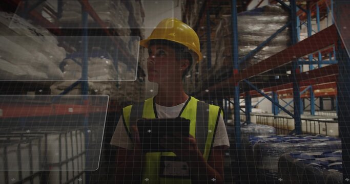Inspecting warehouse worker holding tablet in aisle, wearing yellow hard hat and hi-vis vest, HUD