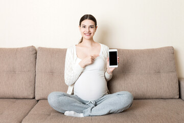 Pregnant woman showing smartphone with black screen in sofa