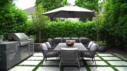 Outdoor dining area with grill and seating arrangement surrounded by lush greenery and overhead shade