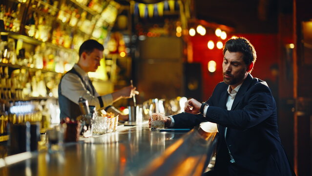 Pub client enjoying bourbon glass at night closeup. Smiling gentleman paying